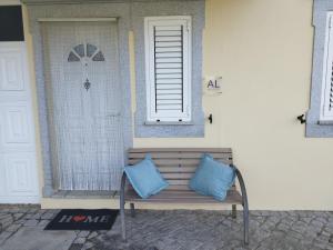 ławka z dwoma niebieskimi poduszkami siedzącymi przed drzwiami w obiekcie Quinta do Pina w mieście Guarda