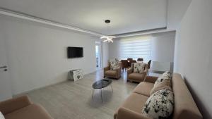 a living room with a couch and chairs and a tv at Site içerisinde deniz manzaralı ve sahile yakın otopark sorunu bulunmayan kiralık daire in Fatsa