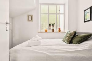- un lit blanc dans une chambre blanche dotée d'une fenêtre dans l'établissement Dinbnb Apartments I Characteristic Townhouse with Bathtub, à Bergen