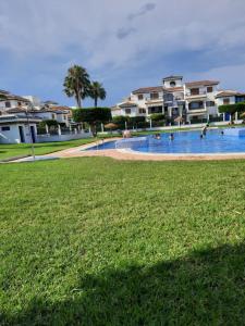 a large swimming pool with people in the grass at Chalet adosado con piscina in Vera