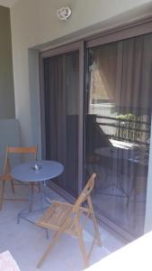 eine Terrasse mit einem Tisch, einem Stuhl und einem Glasfenster in der Unterkunft Sivota apartments Parthenia in Syvota