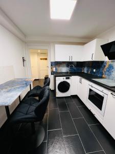 una cucina con mobili bianchi, tavolo e sedie di Souterrain 2 Zimmer Wohnung Freiburg Seepark a Friburgo in Brisgovia