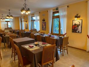 un comedor con mesas, sillas y ventanas en Hotel Col Serena, en Etroubles