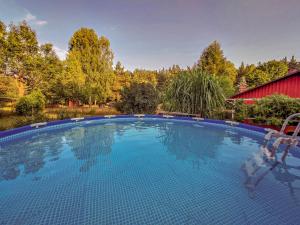 a large swimming pool in front of a red barn at Cisze Kamieniec in Kamieniec