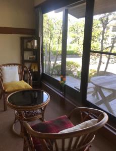 sala de estar con sillas, mesa y ventana en Pension Amagiji, en Izu