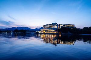 a building on the water with the lights on at Aki Grand Hotel & Spa in Miyajima