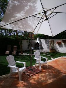 due sedie bianche e un ombrellone su un patio di Villetta al mare a Marsala