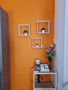 una parete arancione con tre specchi e un tavolo con fiori di Villetta al mare a Marsala