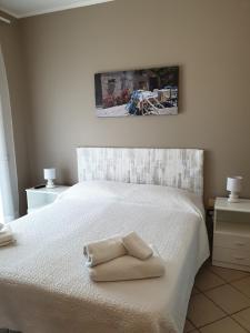 un letto bianco con due asciugamani pieghevoli sopra di Villetta al mare a Marsala