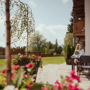 uma mulher sentada numa mesa num jardim em Hotel Leonard em Nova Ponente