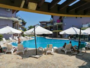 a swimming pool with people sitting in chairs and umbrellas at Casa do Farol - апартамент с басейн до плажа на къмпинг "Градина" in Chernomorets