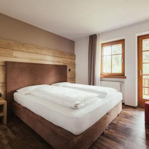 a bedroom with a large white bed with a wooden headboard at Hotel Leonard in Nova Ponente
