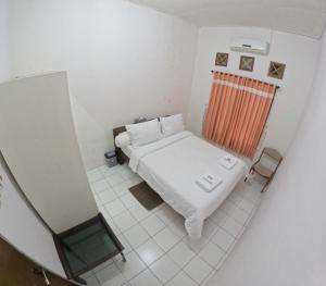 Habitación blanca pequeña con cama y ventana en Mendiro Griya Syariah, en Ngemplak