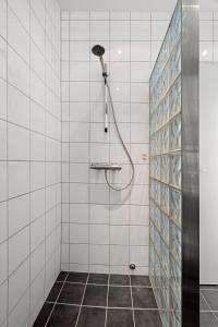 a shower with a shower head in a white tiled bathroom at Seaview studio w/terrace&parking in Tromsø