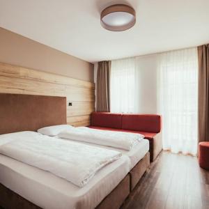 a bedroom with two beds and a red couch at Hotel Leonard in Nova Ponente