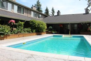 a swimming pool in a yard next to a house at Sunshine Lodge Inn in Gibsons