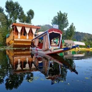 a small boat with a house on the water at Green view group of houseboats in Srinagar
