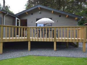 a wooden deck with an umbrella in front of a house at Scenic chalet in Vieuxville with terrace in Vieuxville