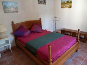 a bedroom with a wooden bed with purple and green sheets at Bienvenue en Provence in Monteux