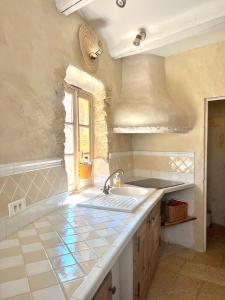 une grande cuisine avec un évier et une fenêtre dans l'établissement La petite maison, à Châteauneuf-du-Pape