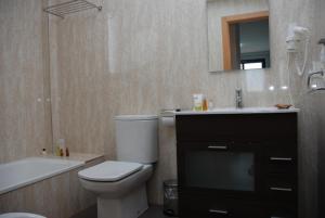 a bathroom with a toilet and a sink and a tub at Aparthotel El Faro in Cullera