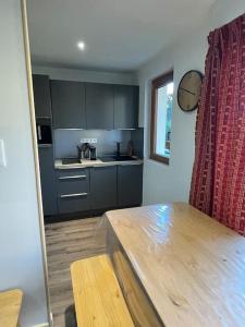 a kitchen with gray cabinets and a wooden table at Très beau T1 refait à neuf in Les Gets