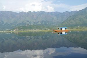 a small boat on the water with mountains in the background at Green view group of houseboats in Srinagar