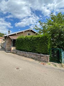 a brick house with a hedge next to a street at Maison au pied de la Roche in Solutré-Pouilly