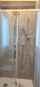 La salle de bains est pourvue d'une douche avec une porte en verre. dans l'établissement Casa bragosso, à Sottomarina