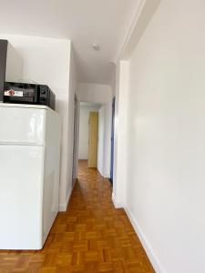 um corredor com paredes brancas, pisos em madeira e um frigorífico em T2 COSY * PARKING * WIFI * PARIS-DISNEY em Villiers-sur-Marne