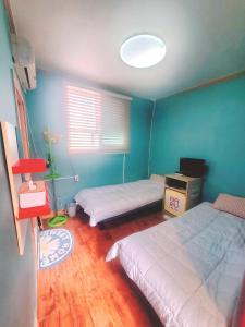 首爾的住宿－韓國納魯旅舍，一间卧室设有两张床和蓝色的墙壁