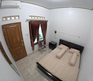 Schlafzimmer mit einem Bett und einer Holztür in der Unterkunft Griyo Mondoliko Homestay Jogja in Demangan