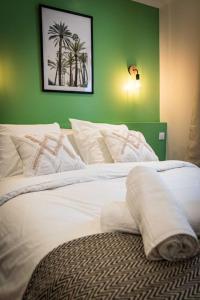 a bedroom with a white bed with a green wall at L'Albatros 001 - Hypercentre * Cosy * Wifi in Saint-Quentin