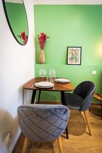 a table and chairs in a room with a green wall at L'Albatros 001 - Hypercentre * Cosy * Wifi in Saint-Quentin