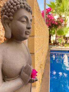 eine Statue einer Frau, die eine Blume neben einem Pool hält in der Unterkunft Boutique Hostal Lorca in Nerja