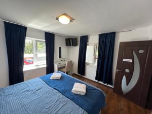 a bedroom with a blue bed with two towels on it at Accommodation Casa Luca in Horezu