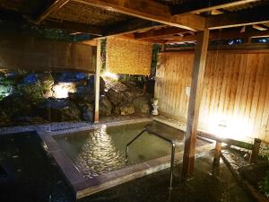a jacuzzi tub in a house with a stone wall at Kasuga Hotel in Nara