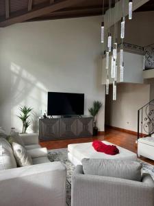 uma sala de estar com mobiliário branco e uma televisão de ecrã plano em Casa dentro del Campo de Golf em Comayagua