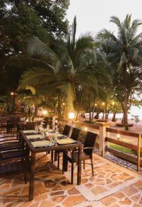 uma mesa de madeira e cadeiras num pátio com palmeiras em La Jolla Luxury Beach Resort em Malawin