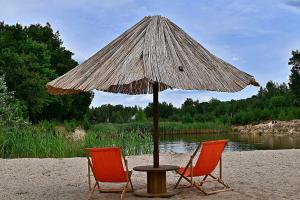 Brochów的住宿－Zacisze u Rysia，海滩上两把椅子和一张遮阳伞下的桌子
