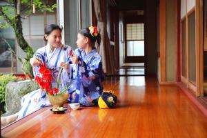 two young girls in kimonos sitting on a wooden floor at 大湖人家　田園風景を眺めなれる、ゆったりとしたゴージャスな屋敷 in Taga