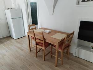 a kitchen with a wooden table with chairs and a refrigerator at Casetta nel Centro Storico in Martina Franca