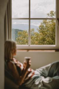 Un uomo e una donna seduti su un letto che guardano fuori dalla finestra di Villa Gloria a Soprabolzano
