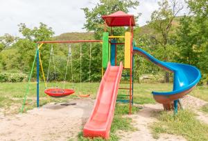 a playground with a slide and swings at Pensiunea Popasul Ursilor in Chişcău