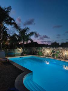 uma piscina à noite com uma parede de pedra em Villa Manzella piscina privata em Cinisi