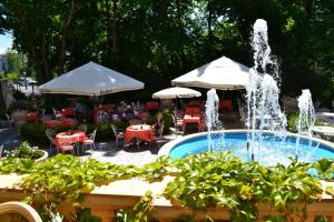 einen Brunnen im Garten mit Tischen und Sonnenschirmen in der Unterkunft Il Gladiatore in Augsburg