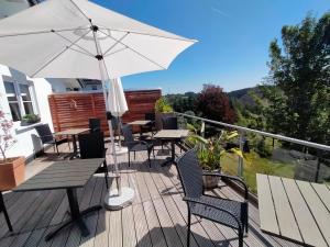 un patio con mesas, sillas y una sombrilla en Landhotel Fernsicht en Winterberg