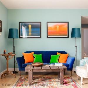 a living room with a blue couch with orange and green pillows at The Corner House in Banchory