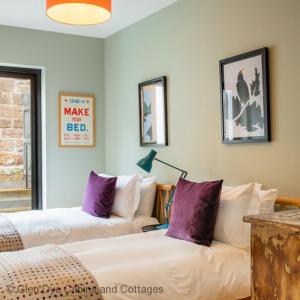 a living room with two beds with purple pillows at The Corner House in Banchory
