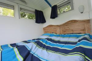 a bedroom with a bed and two windows at Tiny house Roodborstje in Oudesluis